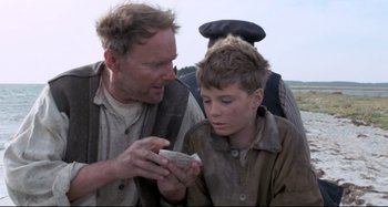Movie still from “Pelle the Conqueror” (1987), directed by Bille August – A man and a young boy looking at something on a cell phone; Close Up shot, Over the shoulder angle