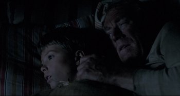 Movie still from “Pelle the Conqueror” (1987), directed by Bille August – An older man and a young boy in a dark room; Close Up shot, Over the shoulder angle