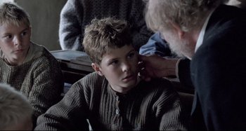Movie still from “Pelle the Conqueror” (1987), directed by Bille August – An older man is helping a young boy with his ear; Close Up shot, Over the shoulder angle