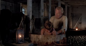 Movie still from “Pelle the Conqueror” (1987), directed by Bille August – An older man and a young boy in a tub; Medium shot, High angle