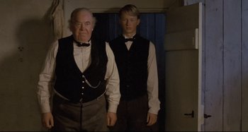 Movie still from “Pelle the Conqueror” (1987), directed by Bille August – A man and a young man standing next to each other; Medium shot, Low angle