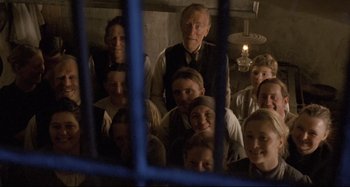 Movie still from “Pelle the Conqueror” (1987), directed by Bille August – A group of people standing in front of a blue fence; Medium shot, High angle