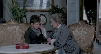 Movie still from “Pelle the Conqueror” (1987), directed by Bille August – An older woman sitting next to a young boy; Medium shot, Over the shoulder angle