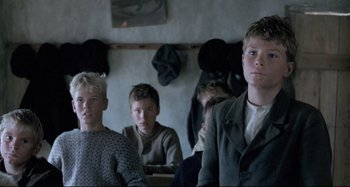 Movie still from “Pelle the Conqueror” (1987), directed by Bille August – A group of young men sitting next to each other in a room; Medium shot, Low angle
