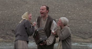 Movie still from “Pelle the Conqueror” (1987), directed by Bille August – A man and two women are playing an accordian; Medium shot, Low angle