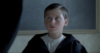 Movie still from “Pelle the Conqueror” (1987), directed by Bille August – A young boy in a school uniform looking up at the sky; Close Up shot, Over the shoulder angle