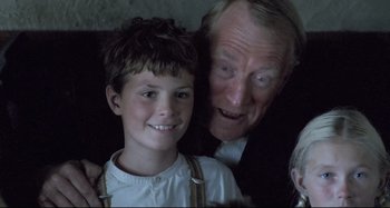 Movie still from “Pelle the Conqueror” (1987), directed by Bille August – An older man and a young boy posing for a picture; Close Up shot, Over the shoulder angle