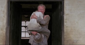 Movie still from “Pelle the Conqueror” (1987), directed by Bille August – An older man holding a young boy in a hat; Medium shot, Low angle