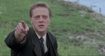 Movie still from “Pelle the Conqueror” (1987), directed by Bille August – A man in a suit and tie pointing to the ground; Close Up shot, Over the shoulder angle