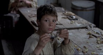 Movie still from “Pelle the Conqueror” (1987), directed by Bille August – A young boy holding a pair of scissors in his hands; Close Up shot, High angle
