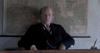 Movie still from “Pelle the Conqueror” (1987), directed by Bille August – An old man sitting at a desk in front of a map; Medium shot, High angle