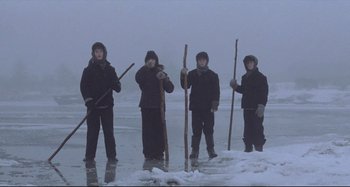 Movie still from “Pelle the Conqueror” (1987), directed by Bille August – A group of people standing on top of a snow covered beach; Wide shot, Low angle
