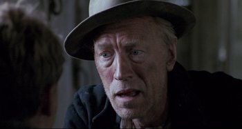 Movie still from “Pelle the Conqueror” (1987), directed by Bille August – An older man wearing a hat and looking sad; Close Up shot, Over the shoulder angle