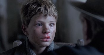 Movie still from “Pelle the Conqueror” (1987), directed by Bille August – A young boy with a bandage on his face; Close Up shot, Over the shoulder angle