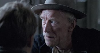 Movie still from “Pelle the Conqueror” (1987), directed by Bille August – An older man wearing a hat and a black jacket; Close Up shot, Over the shoulder angle