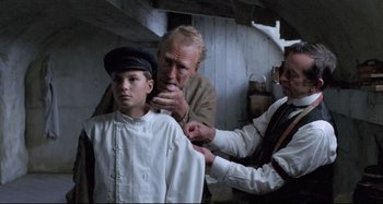 Movie still from “Pelle the Conqueror” (1987), directed by Bille August – A man and a boy getting their hair combed; Medium shot, Low angle
