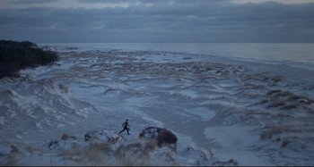 Movie still from “Pelle the Conqueror” (1987), directed by Bille August – A man running on the beach near the ocean; Extreme Wide shot, High angle