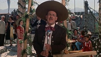 Movie still from “Pepe” (1960), directed by George Sidney – A man wearing a hat and holding a microphone in his hand; Medium shot, Low angle