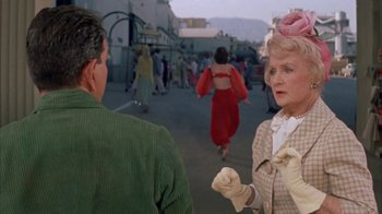 Movie still from “Pepe” (1960), directed by George Sidney – An older man and woman are talking to each other in the street; Medium shot, Over the shoulder angle