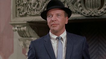 Movie still from “Pepe” (1960), directed by George Sidney – A man wearing a suit and a hat in front of a fireplace; Close Up shot, Low angle