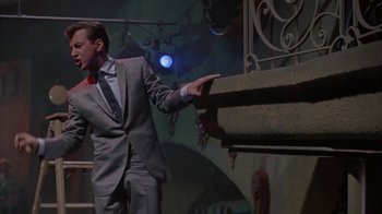 Movie still from “Pepe” (1960), directed by George Sidney – A man wearing a suit and tie standing in front of a wall; Medium shot, Low angle