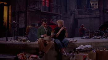 Movie still from “Pepe” (1960), directed by George Sidney – A man and a woman sitting on the ground; Wide shot, High angle