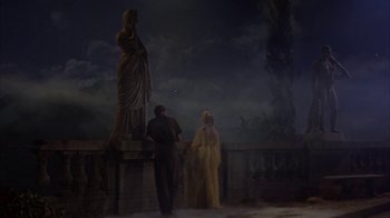 Movie still from “Pepe” (1960), directed by George Sidney – A couple of people standing next to a statue; Wide shot, Low angle