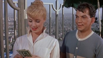 Movie still from “Pepe” (1960), directed by George Sidney – A man and a woman standing next to each other holding money; Medium shot, Over the shoulder angle