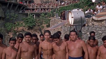 Movie still from “Pepe” (1960), directed by George Sidney – A group of men standing next to each other on a beach; Wide shot, High angle