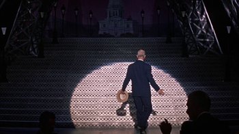 Movie still from “Pepe” (1960), directed by George Sidney – A man walking up a set of stairs with a hat on; Wide shot, Low angle