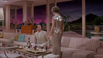 Movie still from “Pepe” (1960), directed by George Sidney – A man and a woman are sitting on a couch in a living room; Wide shot, Low angle