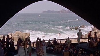 Movie still from “Pepe” (1960), directed by George Sidney – A group of people standing on a beach near the ocean; Extreme Wide shot, High angle