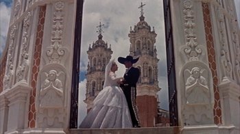 Movie still from “Pepe” (1960), directed by George Sidney – A man and a woman dressed as a bride and groom in front of a church; Wide shot, Low angle