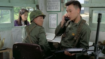 Movie still from “Peppermint Candy” (1999), directed by Lee Chang-dong – Two men in military fatigues talking on a phone; Medium shot, Over the shoulder angle