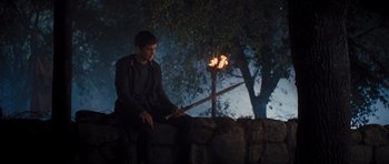 Movie still from “Percy Jackson: Sea of Monsters” (2013), directed by Thor Freudenthal – A man sitting on top of a rock holding an axe; Wide shot, High angle