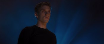 Movie still from “Percy Jackson: Sea of Monsters” (2013), directed by Thor Freudenthal – A man in a black t - shirt is standing in front of a blue background; Close Up shot, Low angle