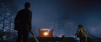 Movie still from “Percy Jackson: Sea of Monsters” (2013), directed by Thor Freudenthal – A man holding a sword in front of a building; Wide shot, Low angle