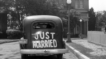 Movie still from “Period of Adjustment” (1962), directed by George Roy Hill – A black and white photo of a just married car; Wide shot, High angle