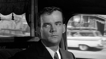 Movie still from “Period of Adjustment” (1962), directed by George Roy Hill – Black and white photograph of a man wearing a suit and tie; Close Up shot, Over the shoulder angle