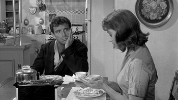 Movie still from “Period of Adjustment” (1962), directed by George Roy Hill – A man and a woman sitting at a table with plates of food in front of them; Medium shot, Over the shoulder angle