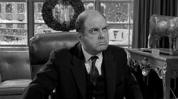 Movie still from “Period of Adjustment” (1962), directed by George Roy Hill – A man sitting in a chair in front of a window; Medium shot, Low angle