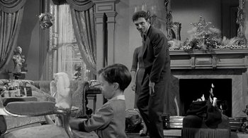 Movie still from “Period of Adjustment” (1962), directed by George Roy Hill – A man and a boy standing in front of a fireplace; Medium shot, Over the shoulder angle
