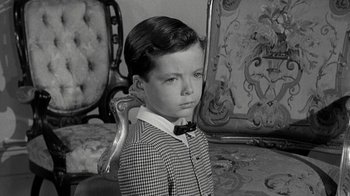 Movie still from “Period of Adjustment” (1962), directed by George Roy Hill – A little boy wearing a suit and bow tie in a room; Close Up shot, High angle