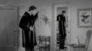 Movie still from “Period of Adjustment” (1962), directed by George Roy Hill – A man in a long coat standing in front of a mirror; Medium shot, Over the shoulder angle