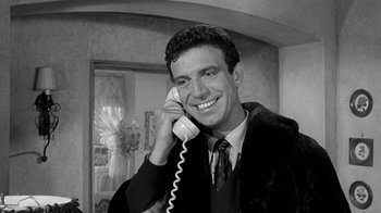 Movie still from “Period of Adjustment” (1962), directed by George Roy Hill – A man smiling while holding a phone up to his ear; Close Up shot, Low angle