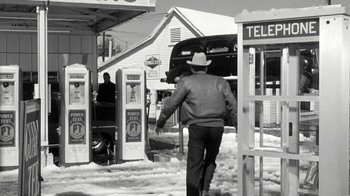 Movie still from “Period of Adjustment” (1962), directed by George Roy Hill – A man in a cowboy hat walking in front of a gas station; Wide shot, Low angle