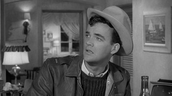 Movie still from “Period of Adjustment” (1962), directed by George Roy Hill – A black and white photo of a man wearing a cowboy hat; Close Up shot, Over the shoulder angle