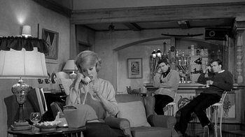 Movie still from “Period of Adjustment” (1962), directed by George Roy Hill – A man and a woman are sitting in a living room; Wide shot, High angle