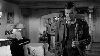 Movie still from “Period of Adjustment” (1962), directed by George Roy Hill – A man standing in front of another man holding a drink; Medium shot, Over the shoulder angle
