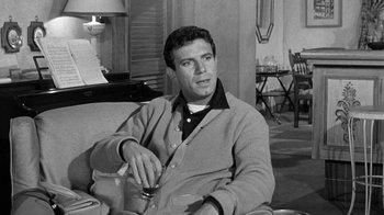 Movie still from “Period of Adjustment” (1962), directed by George Roy Hill – Black and white photograph of a man sitting on a couch; Medium shot, High angle